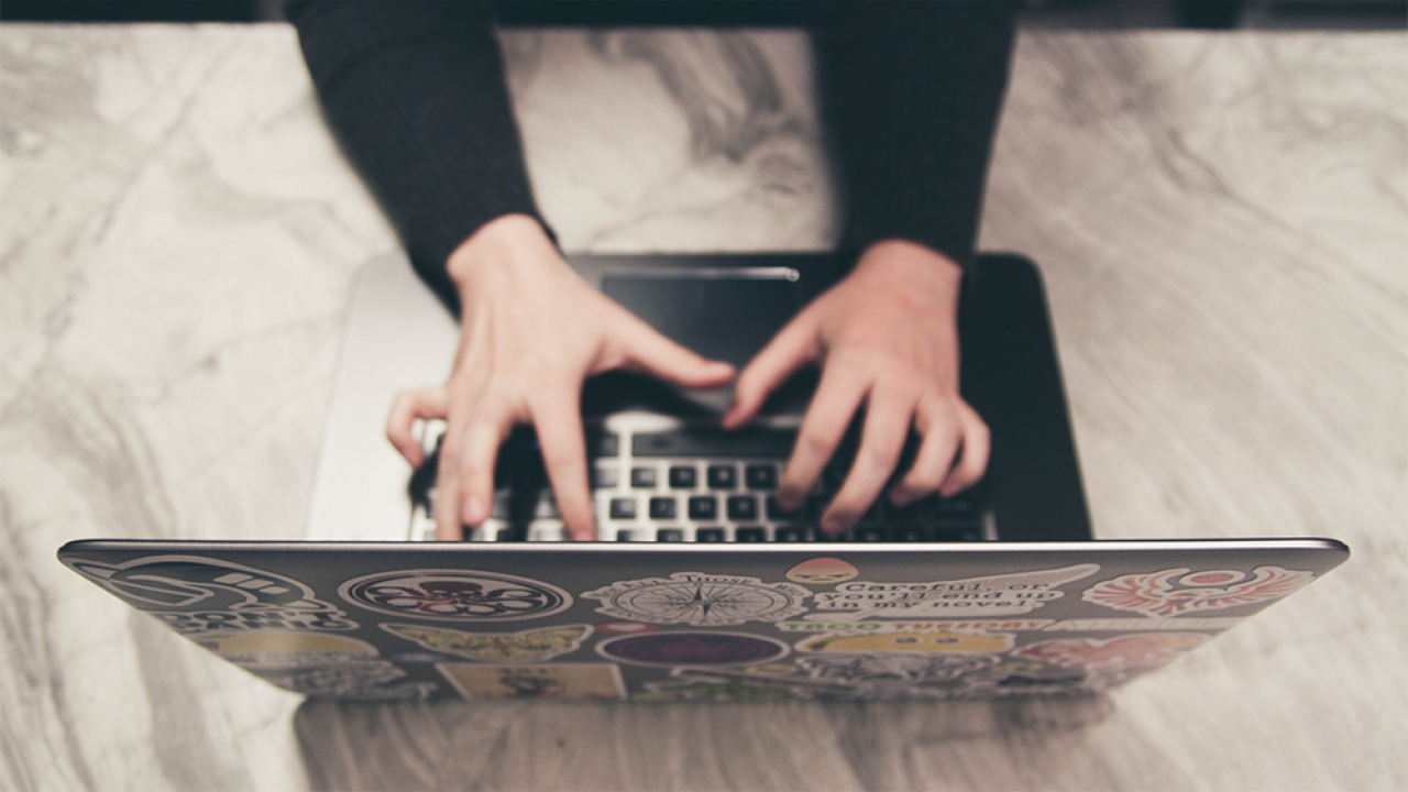 pair of hands writing an email on a laptop