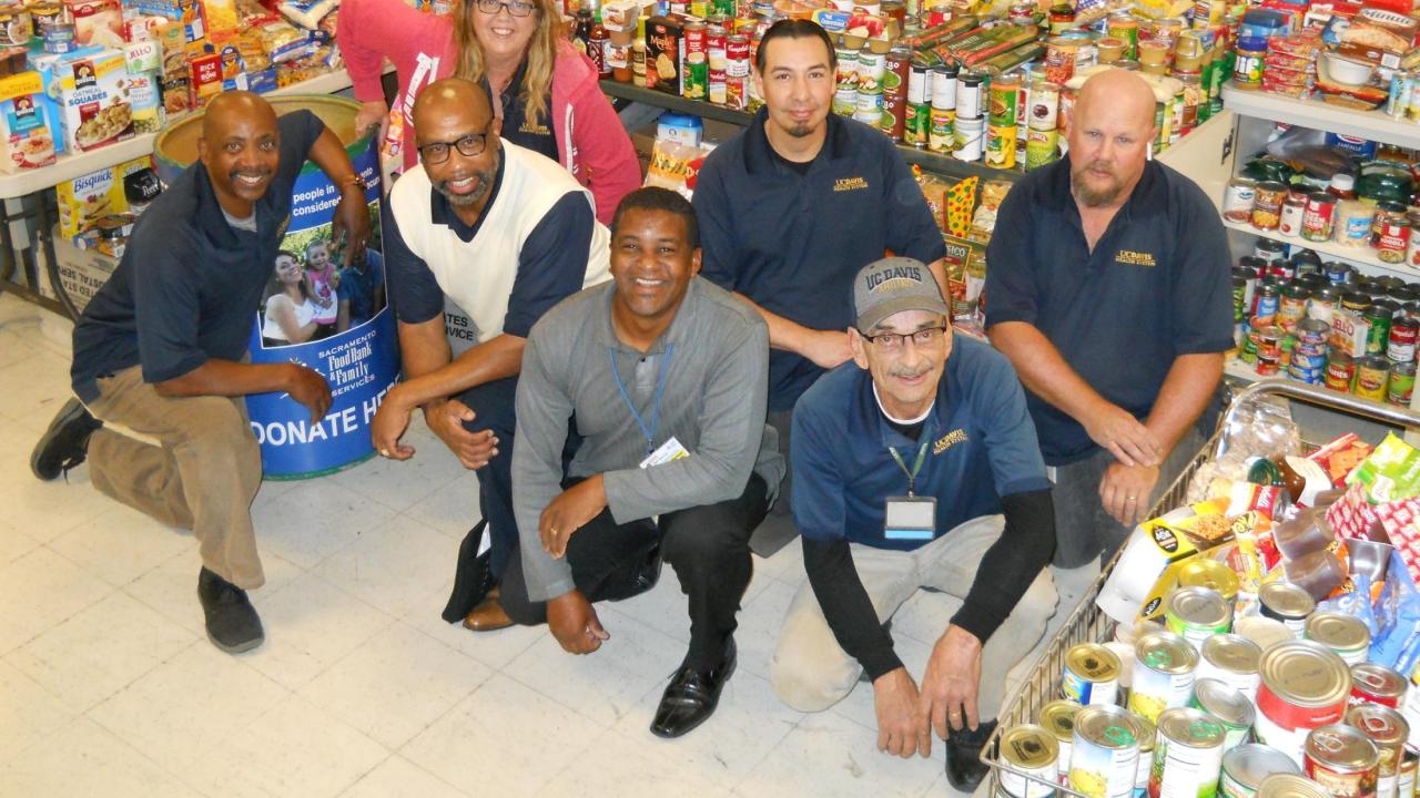 Mail Services employees pose by food donations