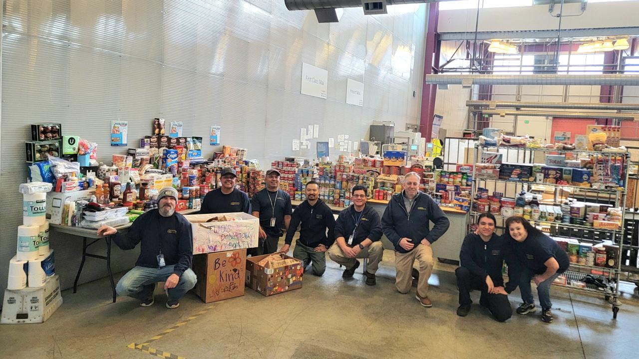 Members of the Campus Mail Services team pose with a large collection of food and non-perishable items.