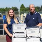 two uc davis employees stand alongside a pile of printers as part of the HP printer exchange event